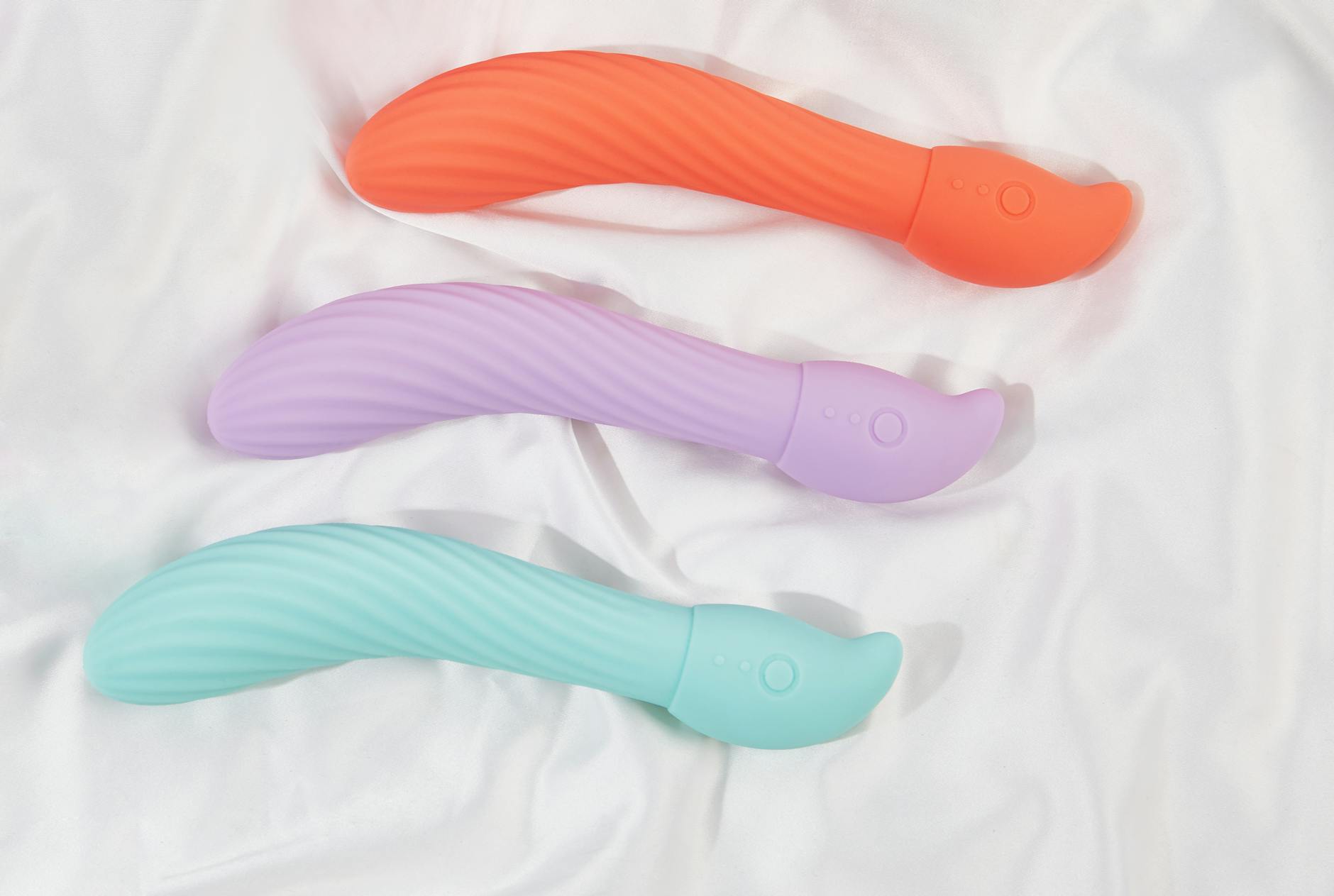 Woman with glasses holding blue and pink silicone vibrators thoughtfully