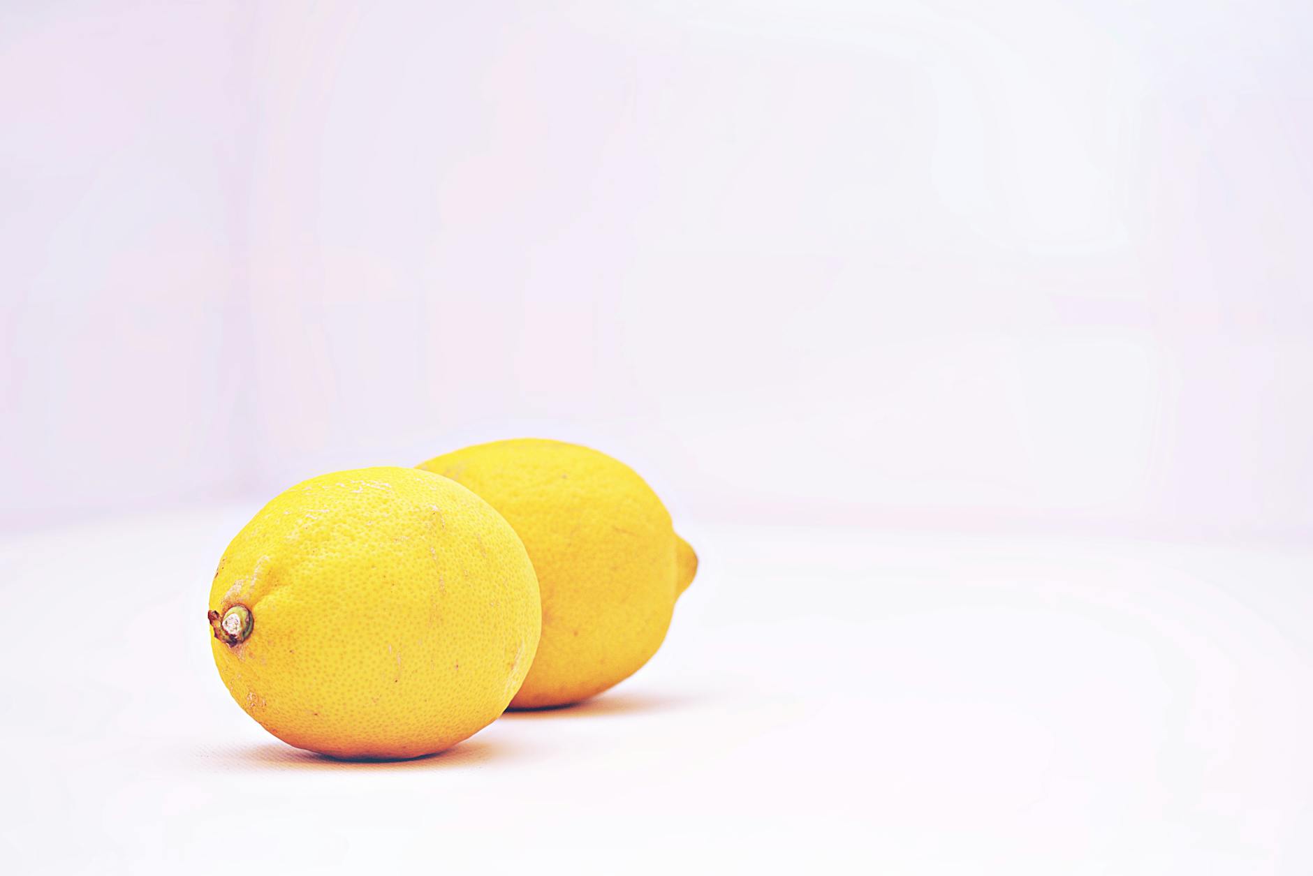 Two vibrant lemons against a white background, symbolizing freshness and sensation