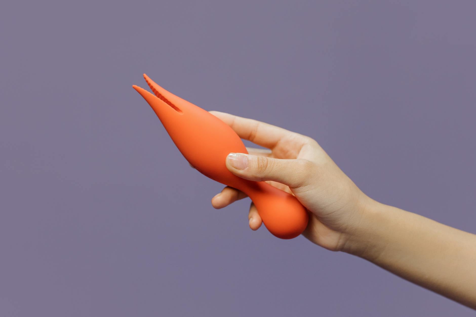 A hand holding a bright lemon vibrator against a purple backdrop, symbolizing modern intimacy solutions for couples