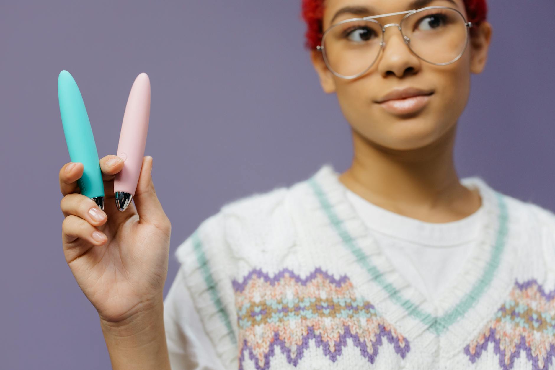 Mulher segurando vibradores coloridos contra fundo roxo minimalista