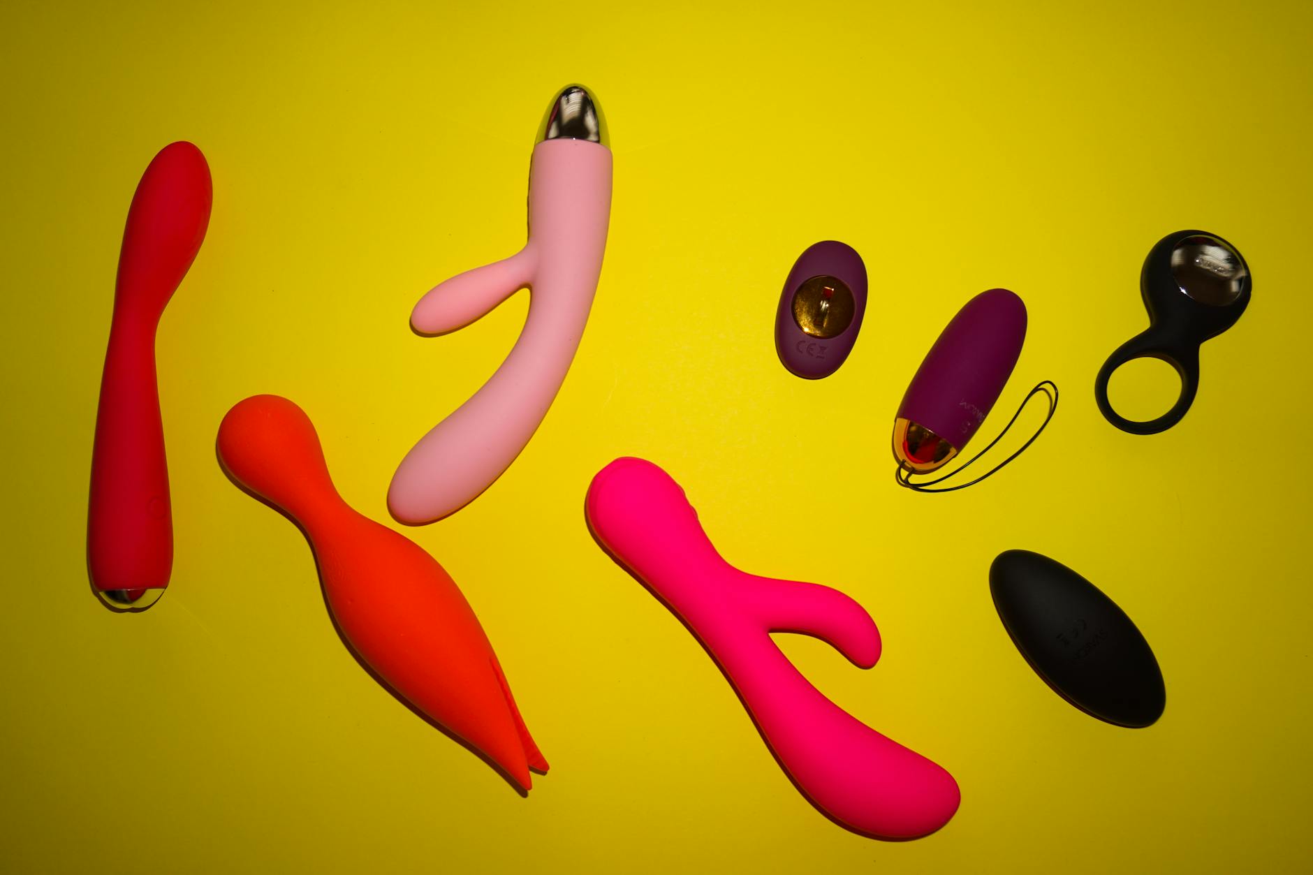 Exibição vibrante de vários brinquedos sexuais de silicone em fundo amarelo