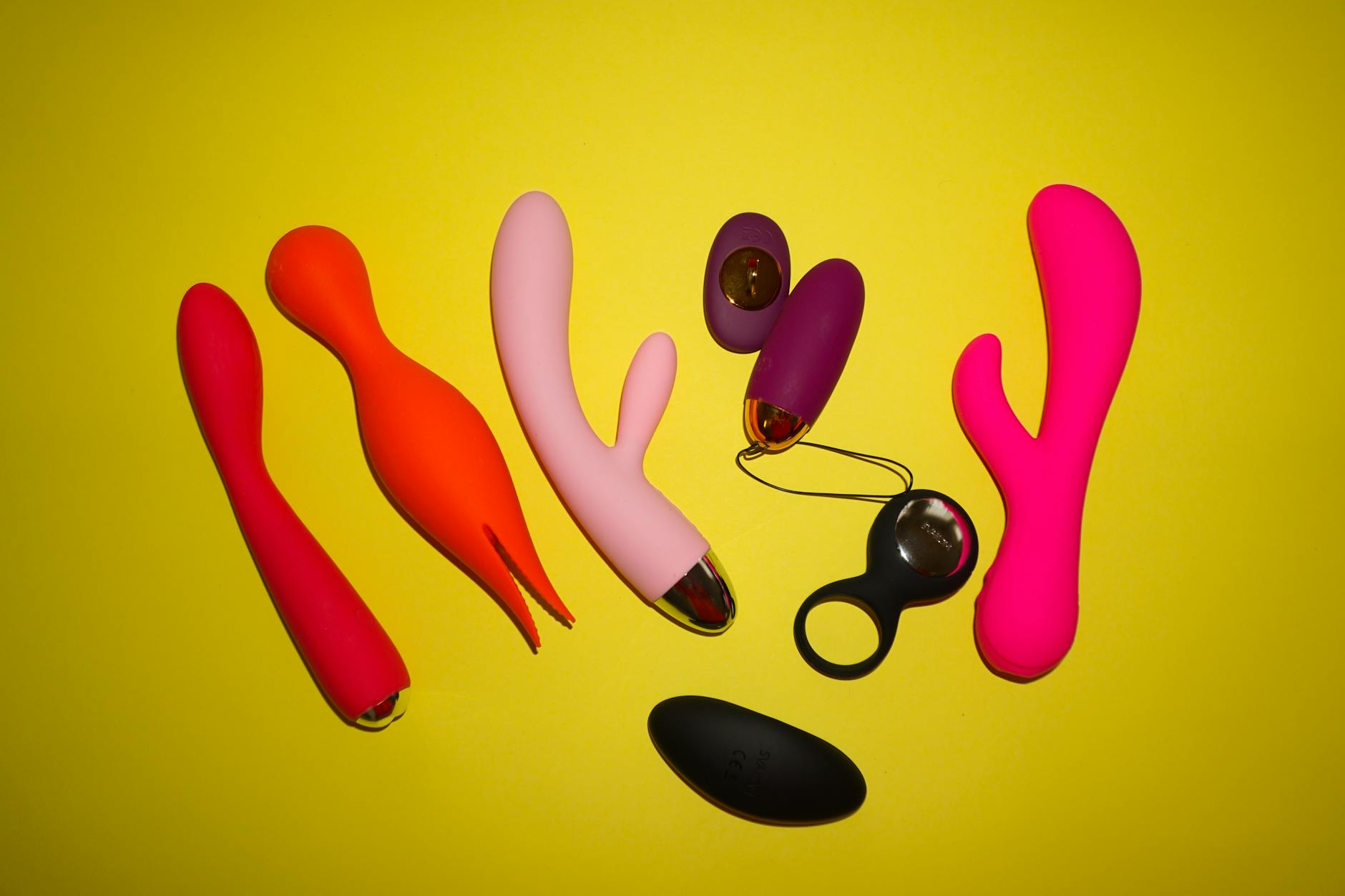 Colorful silicone vibrators and lemon-shaped toys on a bright yellow background